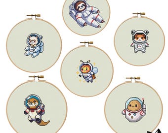 Puede incluir: Conjunto de seis patrones de bordado en aro que presentan varios animales con trajes de astronauta. Los animales incluyen un perezoso, una llama, una abeja, un hámster, una nutria y una patata. Cada aro es beige con un fondo blanco.