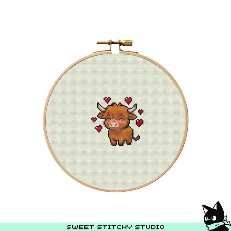 May include: A cross-stitch embroidery hoop featuring a brown Highland cow with a pink blush and surrounded by red hearts. The text "SWEET STITCHY STUDIO" is at the bottom. The hoop is made of wood and has a metal clasp.