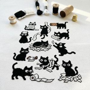 May include: A cross-stitch design with black cat motifs in different poses, such as wrapped in bandages, playing with toilet paper, and relaxing. The image also shows spools of thread, a thimble, and a cardboard tube.