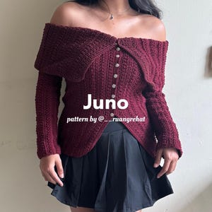 Peut inclure: Un pull en crochet bordeaux à épaules dénudées avec un devant boutonné et une ourlet pointu. Le pull s'appelle "Juno" et le modèle est de "@___ruangrehat".
