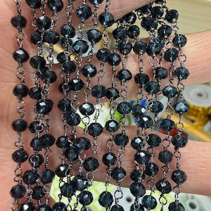 May include: Strands of dark blue faceted beads strung on silver-colored wire. The beads are a deep, translucent color, catching the light and creating a sparkling effect. The beads are uniform in size and shape, and the wire is delicate.