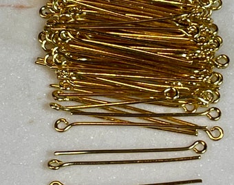 May include: A large quantity of gold-colored head pins with a loop at one end. The head pins are arranged in a stack, with the loops facing outward. The head pins are about 1 inch long.