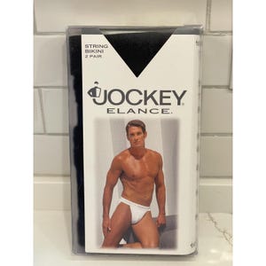 May include: A package of black string bikinis, two pairs included. The packaging features the "Jockey Elance" logo and a photo of a person wearing a white string bikini. Text on the package reads "String Bikini 2 Pair."