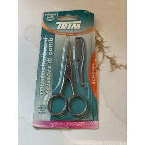 May include: TRIM mustache scissors and comb set. The set includes stainless steel scissors and a small comb, packaged on a green and orange card. The packaging includes the text "mustache beard scissors & comb" and "scissors".