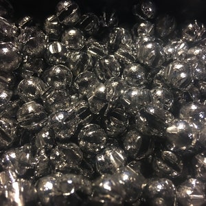 May include: A close-up image of a large quantity of small, round, silver-colored metal fishing sinkers.