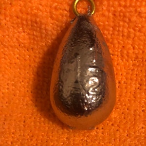 May include: A silver teardrop-shaped fishing sinker with a gold loop at the top.