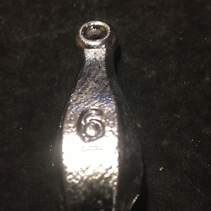 May include: A silver fishing sinker with a loop at the top and the number 6 printed on the side.