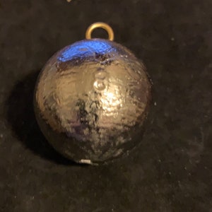 May include: A silver-colored, spherical fishing weight with a textured surface. It has a small, gold-colored loop at the top for attaching to fishing line. The weight has the number "8" stamped on its surface.