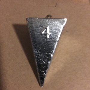 May include: A silver-colored, triangular fishing sinker with the number "4" embossed on it.