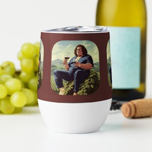 Op de afbeelding: Een roestvrijstalen wijnglas met een bruine achtergrond en een afbeelding van een persoon die in een wijngaard zit met een glas wijn in de hand. Het glas heeft een witte onderkant.