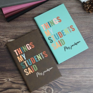 May include: Two brown leather journals with the text "Things My Students Said" in colorful letters. The text is followed by the name "Mrs. Jackson".