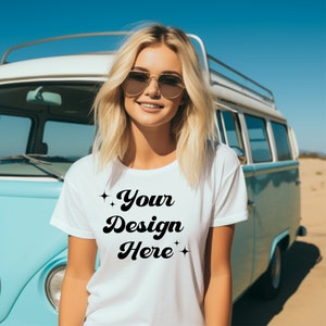 May include: A white t-shirt with the text "Your Design Here" in a retro font. The shirt is being worn by a person with blonde hair and sunglasses, standing in front of a blue and white van.