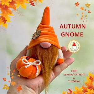 May include: An orange autumn gnome with a long, orange beard and a matching hat. The gnome has a pink nose and is holding a small orange pumpkin with a white bow. The image also includes the text "AUTUMN GNOME".