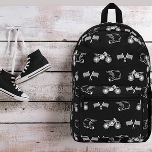 May include: Black backpack with a white repeated pattern of motocross helmets, motorcycles, and crossed flags.