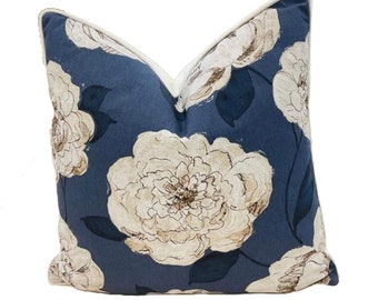 May include: A blue throw pillow with a white floral pattern. The pillow has a white border.