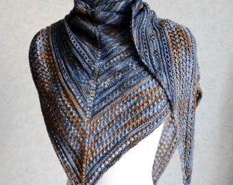 May include: A blue and brown knitted shawl with a lacy pattern. The shawl is draped over a white mannequin.