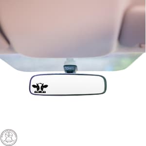 May include: A black rearview mirror with a cow sticker on the glass. The sticker shows two cows kissing.