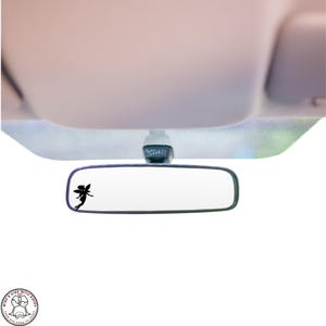 May include: A black silhouette of a fairy is on the rearview mirror of a car. The mirror is hanging from the ceiling of the car.