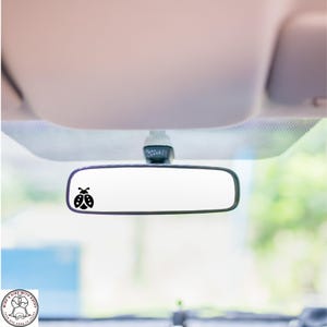 May include: A black ladybug decal on a rearview mirror in a car.