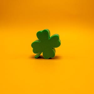 May include: A green four-leaf clover cutout on a bright orange background.
