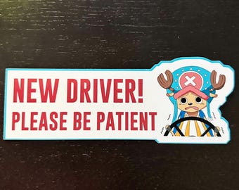 May include: A white and blue car sticker with red text that reads "NEW DRIVER! PLEASE BE PATIENT". A cartoon character with brown antlers and a blue hat is holding a steering wheel.