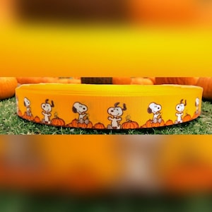 Peut inclure: Ruban jaune avec un motif répété de Snoopy assis sur des citrouilles orange. Le ruban est d'un jaune vif et les personnages de Snoopy sont dans diverses poses. Idéal pour les projets d'artisanat.