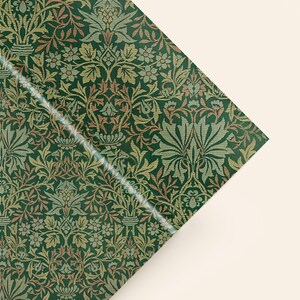 a close-up view of a decorative green and gold patterned fabric or paper with a repeating floral and leaf design.