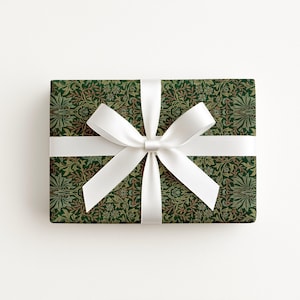 A gift box with a green and white floral pattern and a white ribbon bow tied around it.