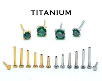 May include: A set of titanium nose rings with green gemstones. The rings are available in different lengths and styles, including plain and with a gemstone.