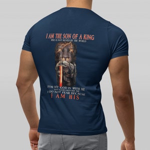 Pode incluir: Uma camiseta azul marinho com um gr&aacute;fico de um le&atilde;o segurando uma espada. O texto na camiseta diz "Eu sou o filho de um rei que n&atilde;o &eacute; movido pelo mundo. Porque o meu Deus est&aacute; comigo e vai &agrave; minha frente. N&atilde;o temo porque sou seu."