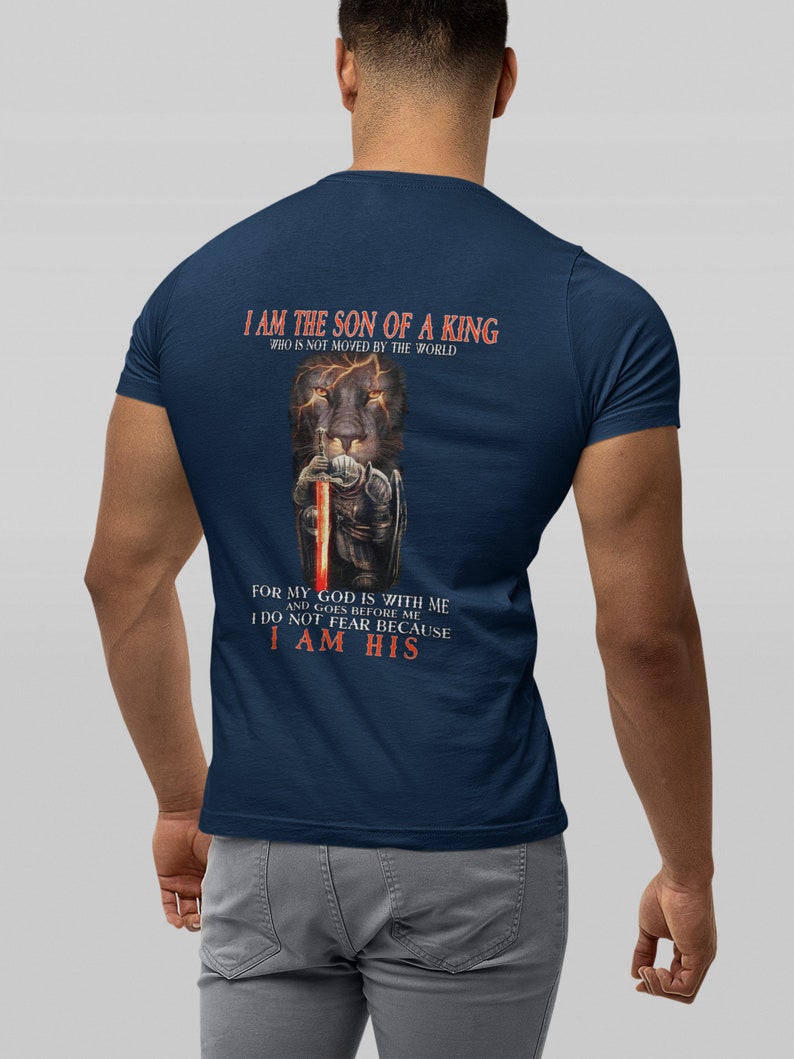 Pode incluir: Uma camiseta azul marinho com um gr&aacute;fico de um le&atilde;o segurando uma espada. O texto na camiseta diz "Eu sou o filho de um rei que n&atilde;o &eacute; movido pelo mundo. Porque o meu Deus est&aacute; comigo e vai &agrave; minha frente. N&atilde;o temo porque sou seu."