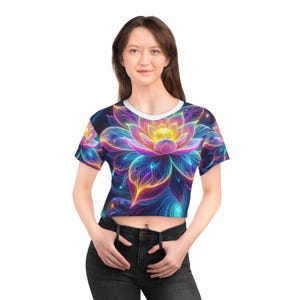 May include: A cropped t-shirt with a colorful, glowing lotus flower design. The shirt is white with a blue background and features a vibrant pink, yellow, and orange flower.