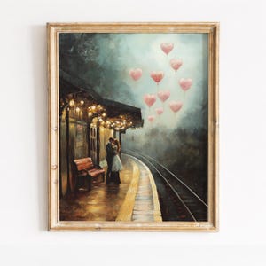 May include: A framed art print depicts a romantic scene at a train station. A couple embraces on the platform, with heart-shaped balloons floating above. The scene is illuminated by warm lights, with a bench and train tracks visible.