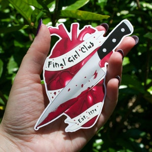 May include: A red heart with a knife through it, with the text "Final Girl Club Est. 1979" on a white banner.