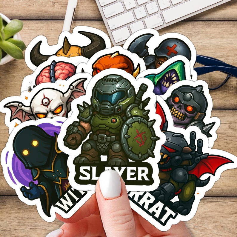 Pode incluir: Uma cole&ccedil;&atilde;o de autocolantes de desenhos animados coloridos com v&aacute;rios personagens de fantasia. Os autocolantes incluem uma figura verde blindada com um escudo, uma caveira e outras figuras monstruosas. A palavra "SLAYER" &eacute; vis&iacute;vel.