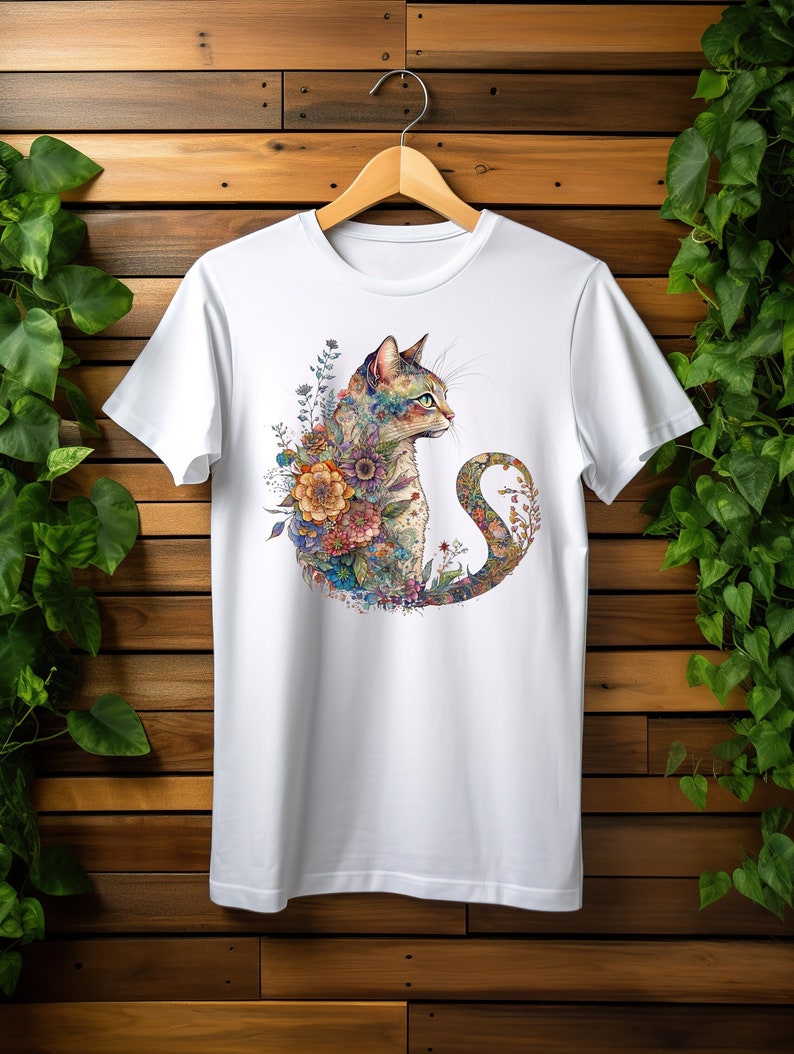 May include: White t-shirt featuring a colourful illustration of a cat surrounded by flowers. The cat is looking to the right and its tail is curled around its body.