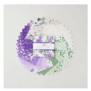 Pode incluir: Uma coleção de quadrados de tecido em tons de roxo, lavanda e verde, dispostos em um padrão circular. O tecido apresenta padrões florais e é centrado em um pacote embrulhado com o texto "Lilac Lane".