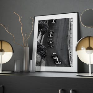 May include: Two brown and white glass table lamps with a white base and a black and white photo of race cars on a track in a black frame on a dark gray surface.