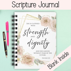 May include: A spiral-bound Scripture Journal with the text "Scripture Journal" at the top. The cover features floral designs, gold accents, and the words "strength and dignity." A pink pen and a black pen are on the left.