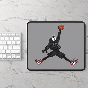 May include: A gray mousepad with a black and red cartoon character wearing red sneakers and holding a basketball. The character is jumping in the air with a surprised expression.