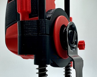 Könnte beinhalten: Ein schwarzer und roter 3D-gedruckter Jig für ein rotierendes Werkzeug mit einem federbelasteten Tauchmechanismus und einer schwarzen Klinge. Der Jig hat eine Basis mit mehreren Löchern und der Text "NEXTGEN WORKSHOP" ist auf der Basis aufgedruckt.