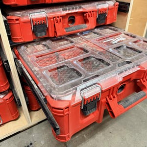 Puede incluir: Cajas de herramientas rojas con tapas transparentes segmentadas apiladas en una unidad de almacenamiento. Las cajas tienen cierres y asas negros. La caja superior está cerrada, mientras que la inferior está parcialmente abierta, revelando compartimentos.