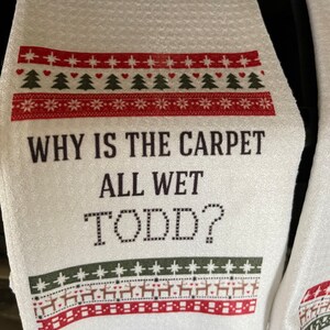 May include: White kitchen towel with a red and green Christmas-themed design. The text "WHY IS THE CARPET ALL WET TODD?" is printed in black.