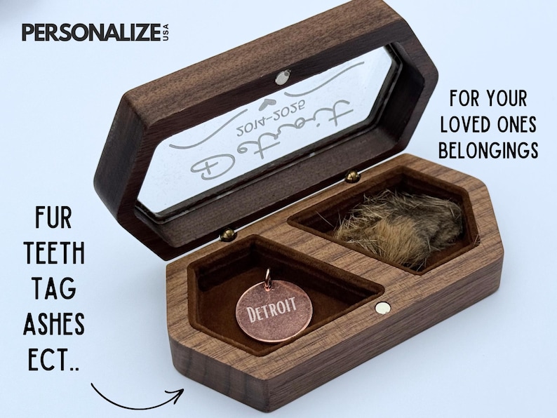 May include: A wooden keepsake box with a hinged lid and two compartments. One compartment contains a tuft of fur, the other a copper Detroit tag. The box is designed to hold cherished items like fur, teeth, tags, or ashes.