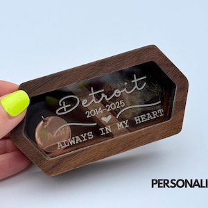 May include: A wooden keepsake box with a clear window, featuring the engraved word "Detroit" and the years 2014-2025. The text "ALWAYS IN MY HEART" is also visible. A small, round copper-colored charm is inside.