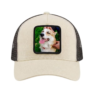 Könnte beinhalten: Beige Trucker-Cap mit schwarzem Mesh-Rücken und einem quadratischen Aufnäher mit einem glücklichen Corgi-Hund. Der Hund hat eine rosa Zunge und wird gestreichelt. Die Kappe ist ein klassischer Stil.