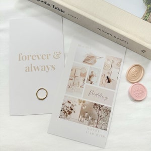 May include: A white card with the text "forever & always" in a beige font. A gold ring is on the card. A second card with a collage of wedding-themed images and the text "Wedding" in cursive. The text "Happily Ever After" is at the bottom of the card. Two wax seals, one pink and one beige, are on the white surface.
