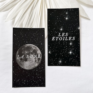 May include: Two black cards with white text and images. The first card features a full moon with the text "LA LUNE" and the second card features a constellation with the text "LES ÉTOILES".