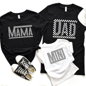May include: Three black t-shirts with white checkered lettering. The shirts say "Mama", "Dad", and "Mini".