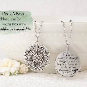 May include: A silver-toned necklace with a detailed, openwork pendant and a delicate chain. The necklace can be worn two ways, as the image text indicates. The second pendant has an inscription from Proverbs 31:25 and a small bird illustration.